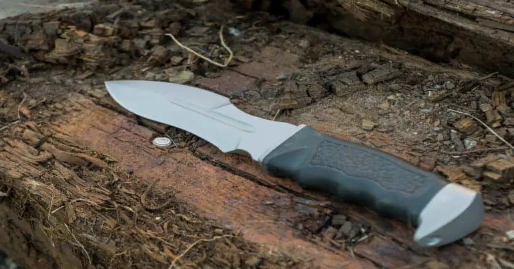 A bushcraft survival knife on a tree stump