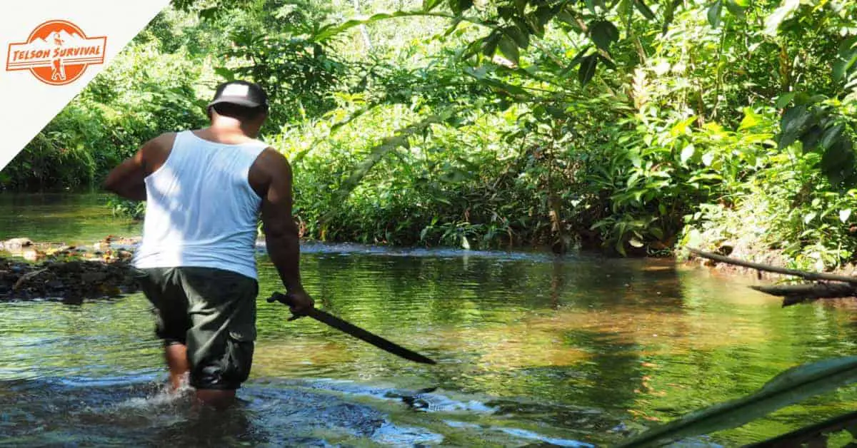 Man using jungle survival gear to navigate a jungle river