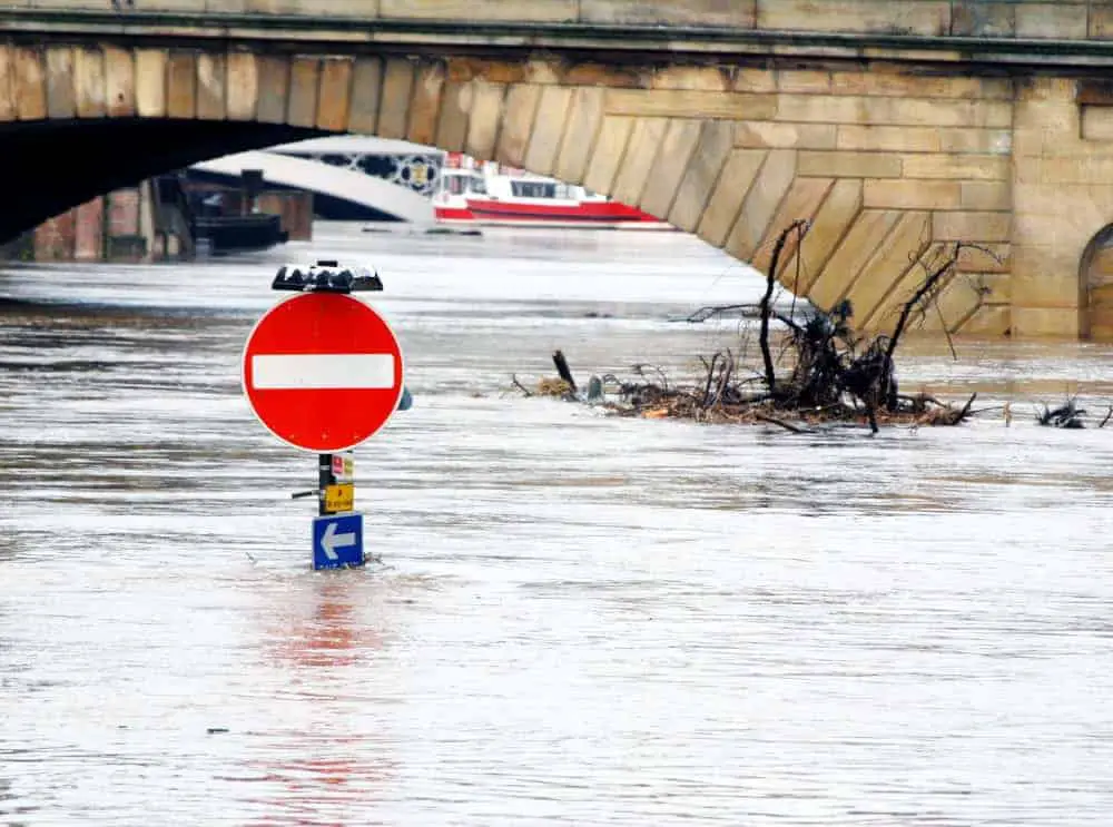 Flooded stop sign on a street near a bridge
